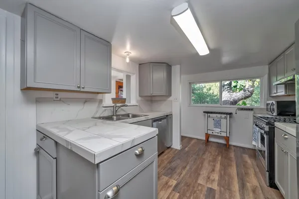 a kitchen with a stove a sink a microwave and wooden cabinets