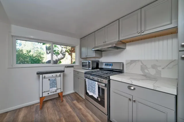 a kitchen with stainless steel appliances granite countertop a stove and a white cabinets