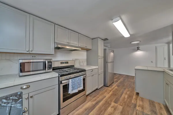 a kitchen with cabinets appliances and a wooden floor