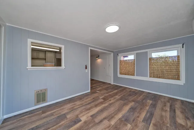 a view of an empty room with a window and wooden floor
