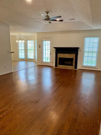 an empty room with wooden floor fireplace and windows