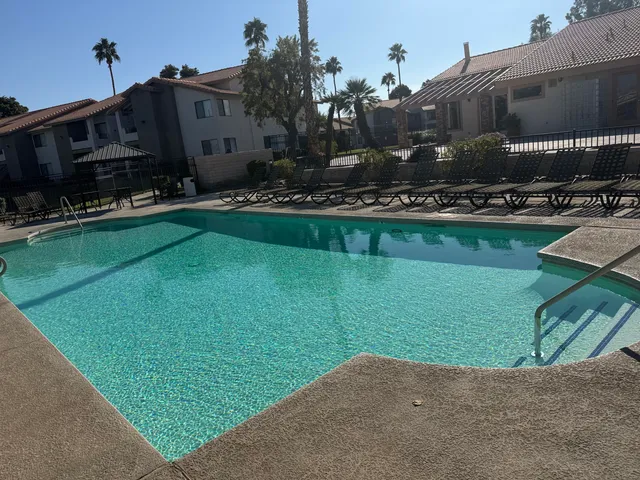 a view of patio with table and chairs under an umbrella with a barbeque