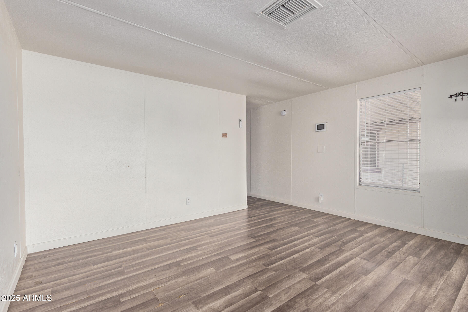 1221 North Dysart Road, Unit 35 Avondale, AZ 85323 - Photo 7 of 22 a view of an empty room with wooden floor and a window