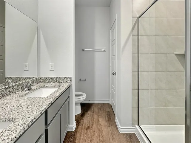 a bathroom with a granite countertop sink a toilet and shower