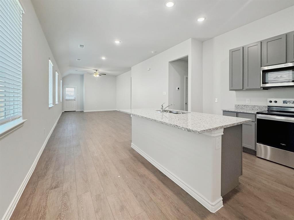 9944 Dynamic Drive Fort Worth, TX 76131 - Photo 5 of 17 a large kitchen with stainless steel appliances kitchen island a sink dishwasher a stove and a refrigerator with wooden floor
