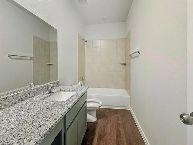 a bathroom with a granite countertop sink a toilet and shower