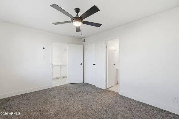 an empty room with ceiling fan and windows