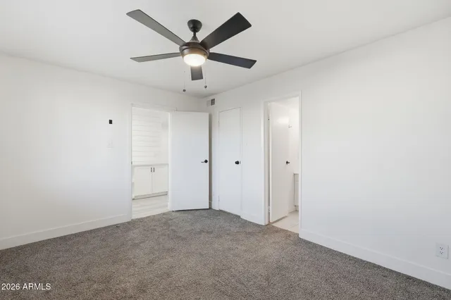 an empty room with ceiling fan and windows