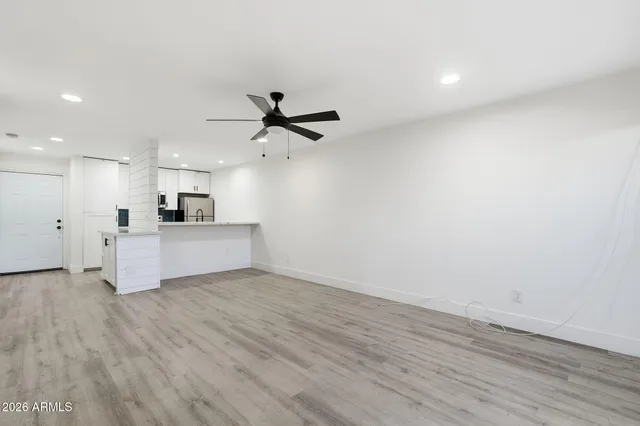 a view of a kitchen with a sink a ceiling fan and stainless steel appliances