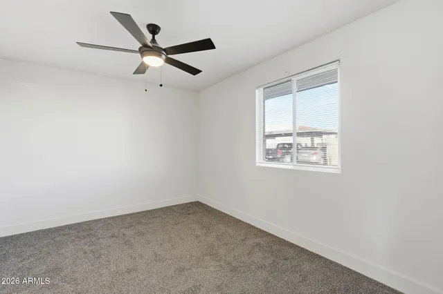 an empty room with a window and a ceiling fan