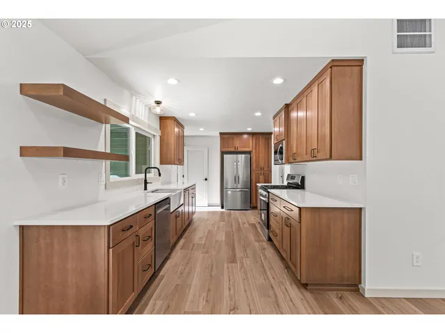 a large kitchen with a large counter top a sink stainless steel appliances and cabinets