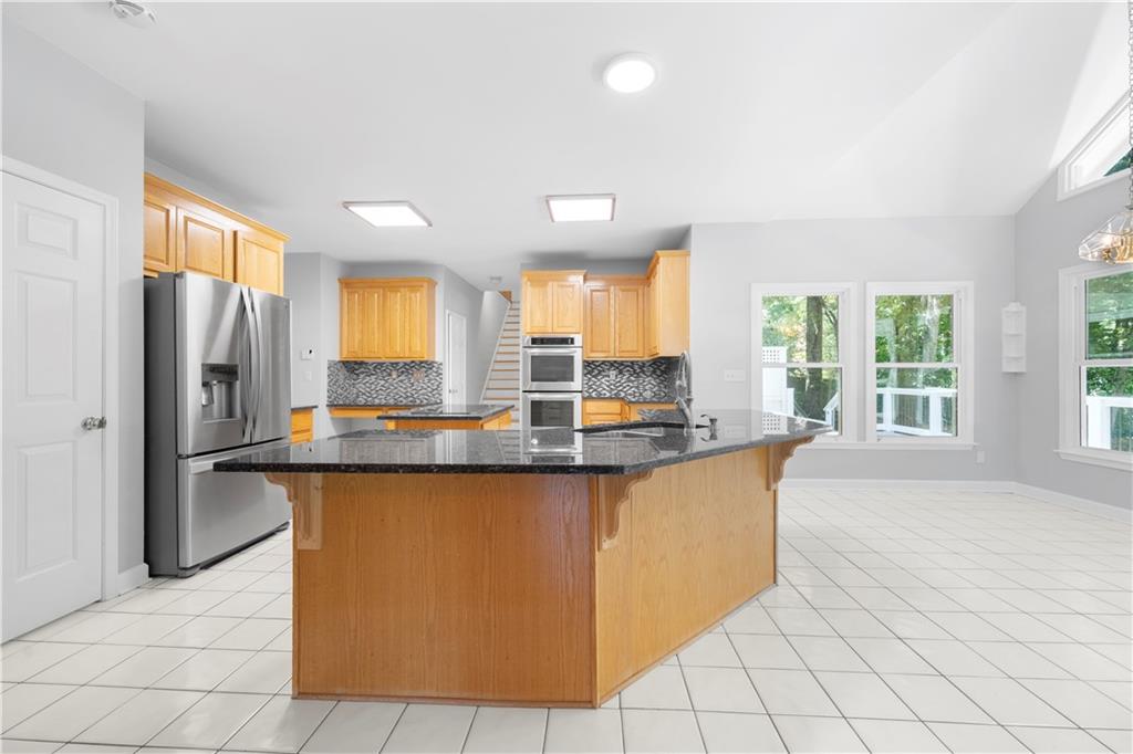 3334 Trails End Road Northeast Roswell, GA 30075 - Photo 11 of 54 a large kitchen with kitchen island granite countertop a stove a sink a refrigerator and white cabinets