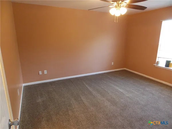 an empty room with a chandelier fan and windows
