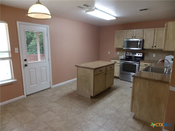 a kitchen with stainless steel appliances granite countertop a stove top oven a sink dishwasher and a microwave oven on the blue kitchen countertops