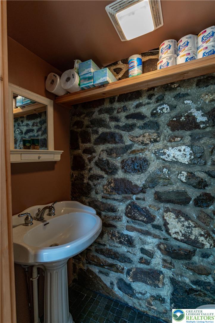 2485 Hieter Road Quakertown, PA 18951 - Photo 57 of 97 A quaint bathroom with a pedestal sink, featuring striking stone accent walls and classic tile flooring.