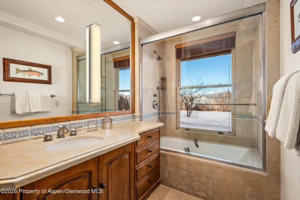 a bathroom with a tub a sink and a large mirror