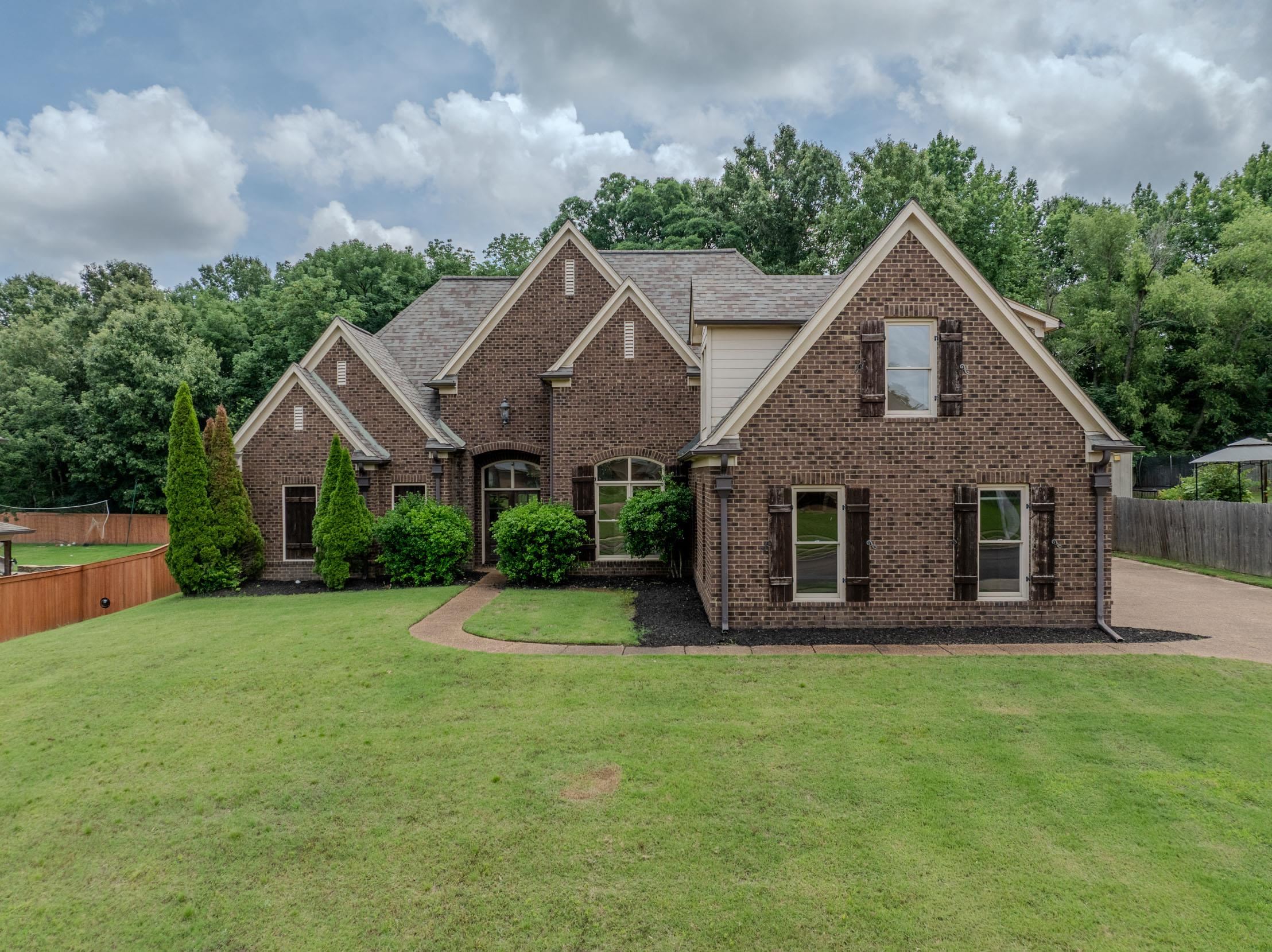 5380 Scarlet Ridge Drive Arlington, TN 38002 - Photo 24 of 35 Brick exterior with multiple gables and dormer windows, featuring dark shutters, a curved concrete pathway, and an expansive lawn