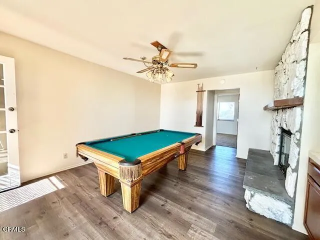 a room with wooden floor pool table and a chandelier