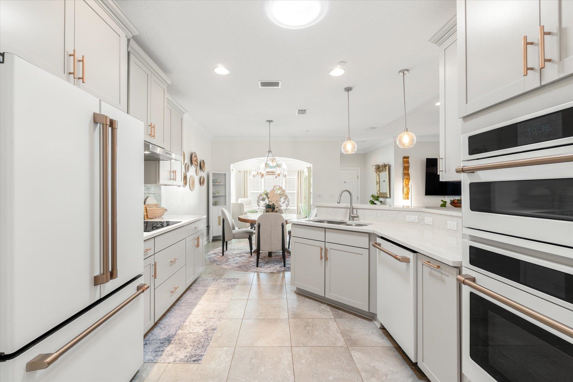 82 Timoga Trail St. Augustine, FL 32084 - Photo 20 of 62 Kitchen featuring white appliances, a chandelier, crown molding, a peninsula, and light stone countertops