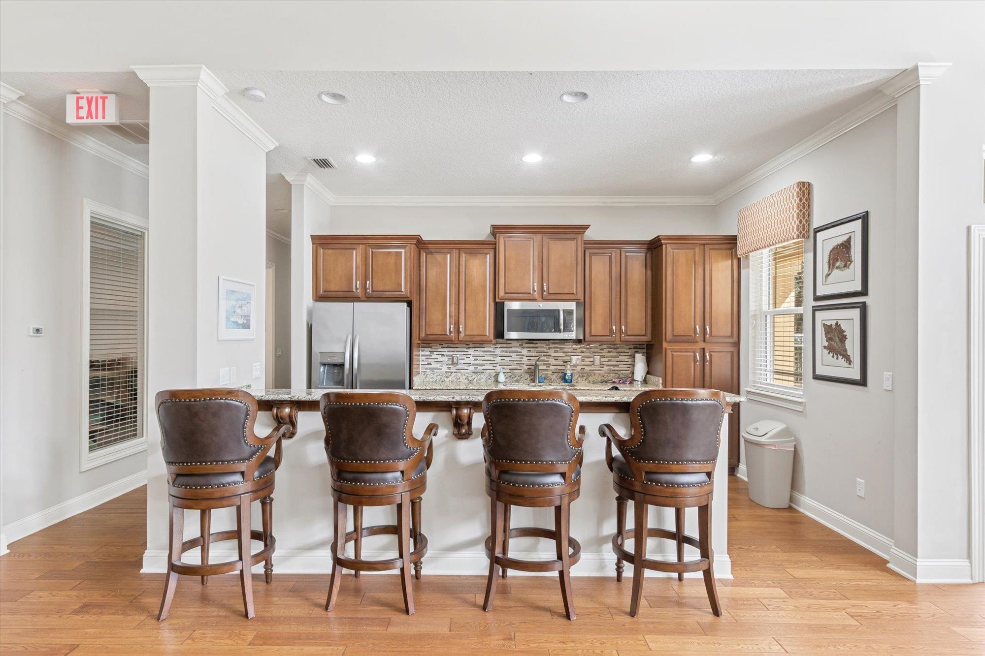 82 Timoga Trail St. Augustine, FL 32084 - Photo 47 of 62 Kitchen featuring wood finish cabinets, a kitchen breakfast bar, stainless steel appliances, decorative backsplash, and light stone counters