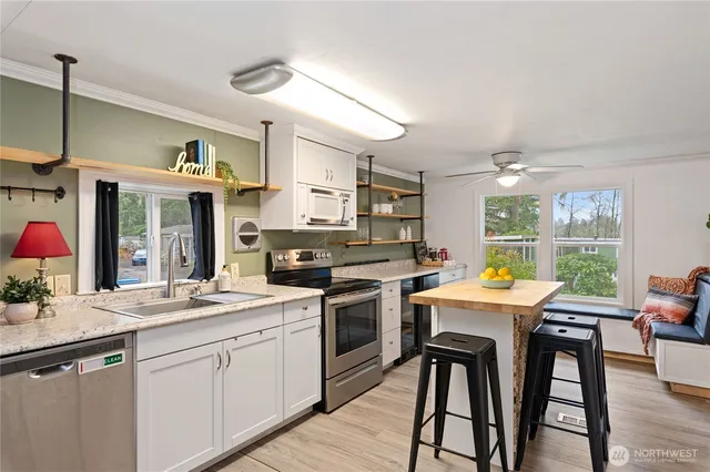 a kitchen with stainless steel appliances granite countertop a stove a sink dishwasher a dining table and chairs with wooden floor