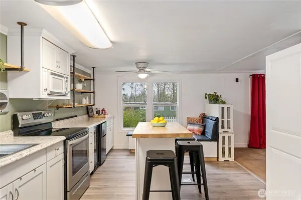 a kitchen with stainless steel appliances granite countertop a stove a refrigerator a kitchen island a sink dishwasher and white cabinets with wooden floor