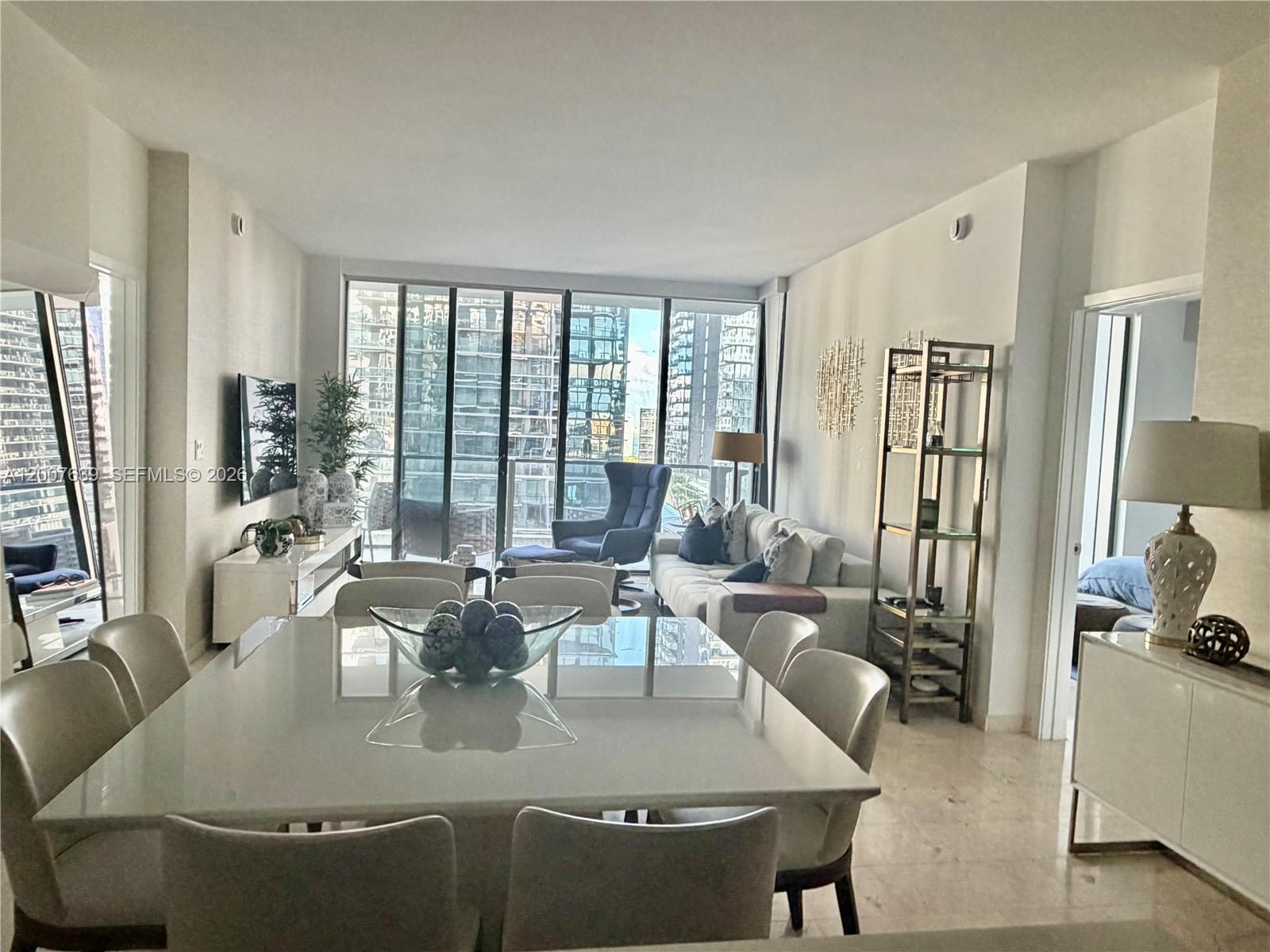 88 Southwest 7th Street, Unit 1109 Miami, FL 33130 - Photo 14 of 40 a view of a dining room with furniture large windows and wooden floor