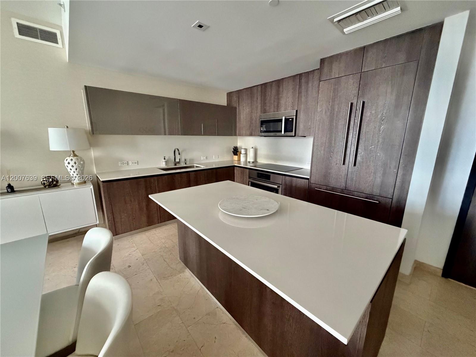 88 Southwest 7th Street, Unit 1109 Miami, FL 33130 - Photo 17 of 40 a kitchen with stainless steel appliances a refrigerator a sink a stove a table and chairs