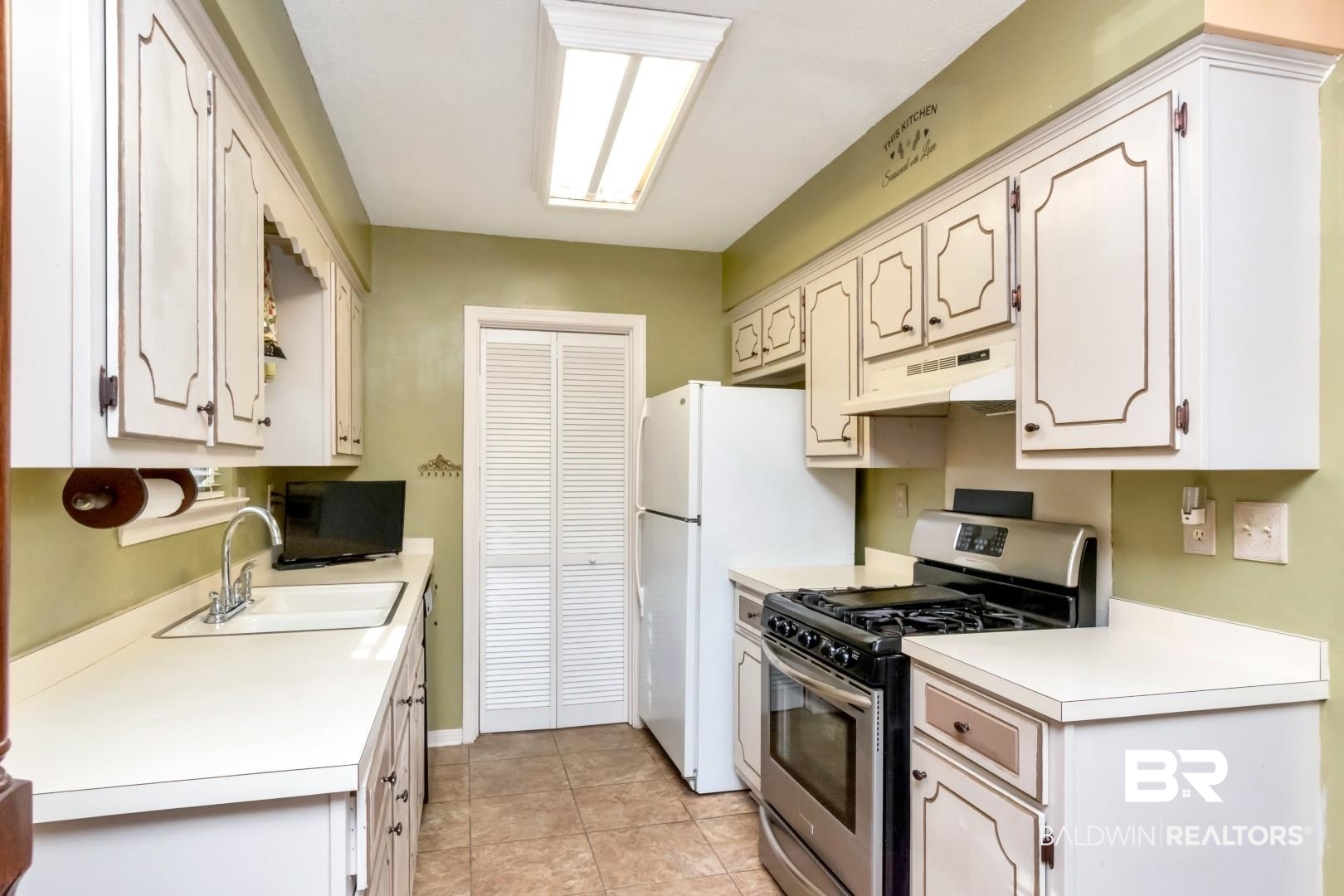 9360 Burnt Tree Drive Mobile, AL 36695 - Photo 10 of 28 Kitchen featuring stainless steel gas range oven, sink, light tile patterned floors, white fridge, and white cabinetry