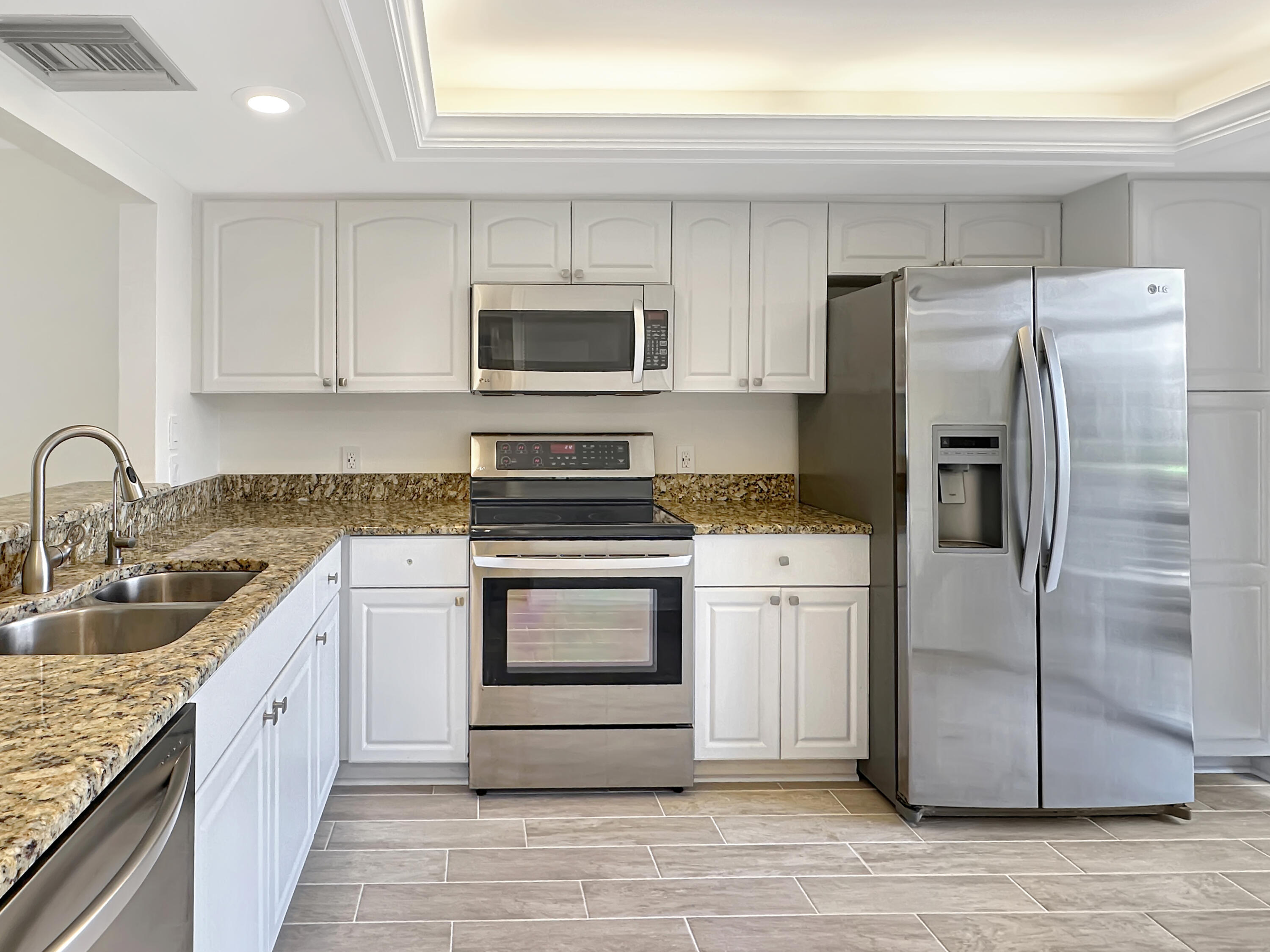 3351 Twin Lakes Terrace, Unit 102 Fort Pierce, FL 34951 - Photo 2 of 21 a kitchen with stainless steel appliances granite countertop a refrigerator sink and microwave