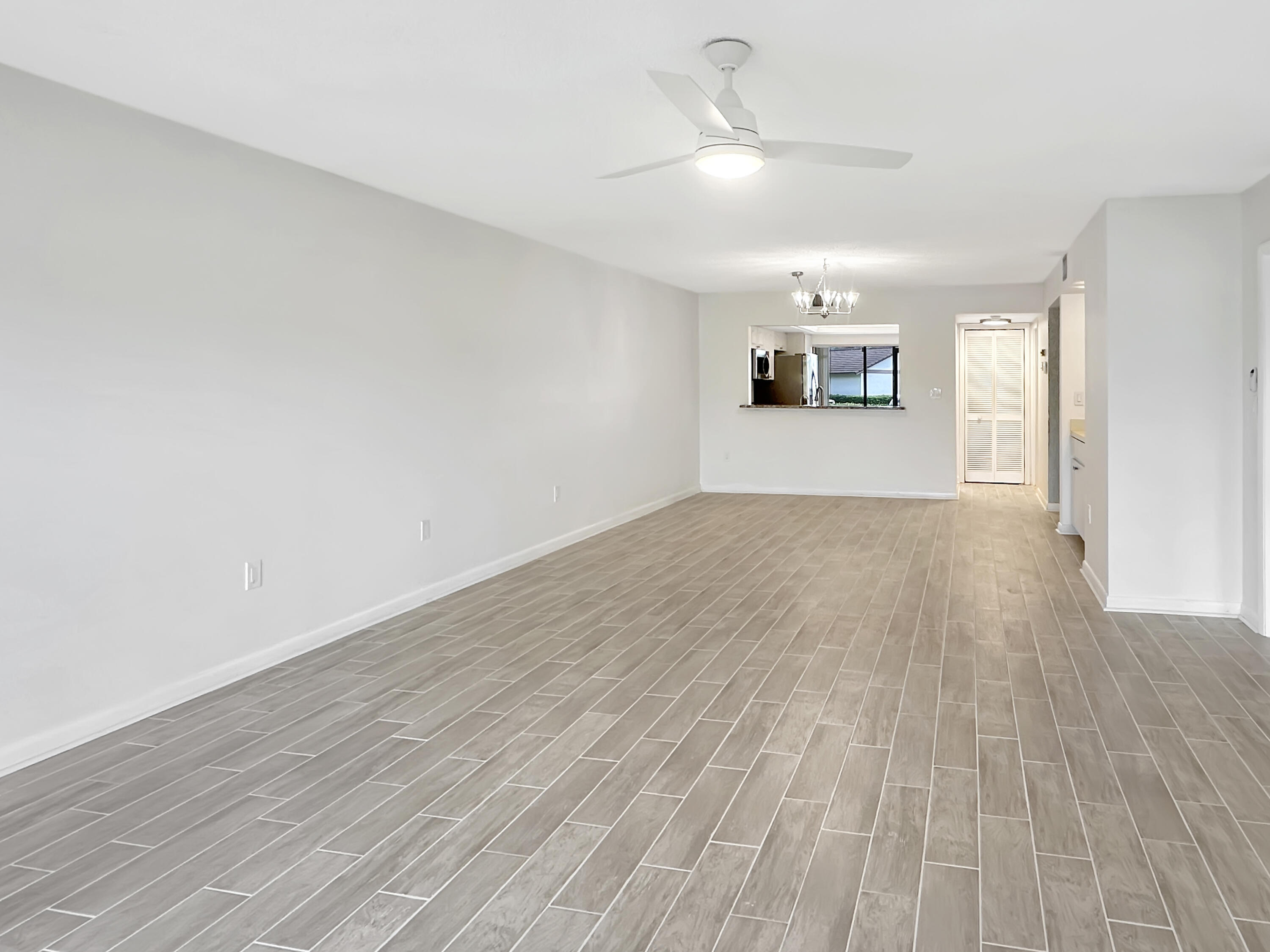 3351 Twin Lakes Terrace, Unit 102 Fort Pierce, FL 34951 - Photo 9 of 21 a view of a livingroom with wooden floor and a ceiling fan