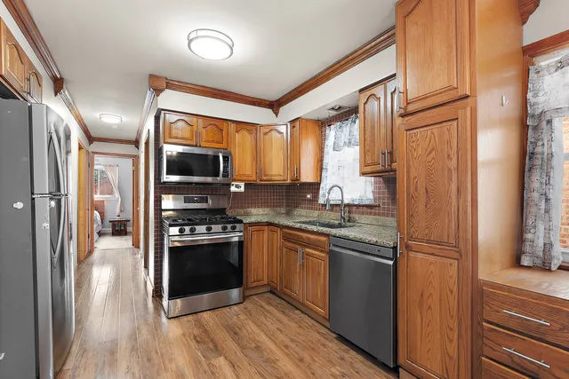 a kitchen with stainless steel appliances granite countertop a stove a sink dishwasher and cabinets with wooden floor