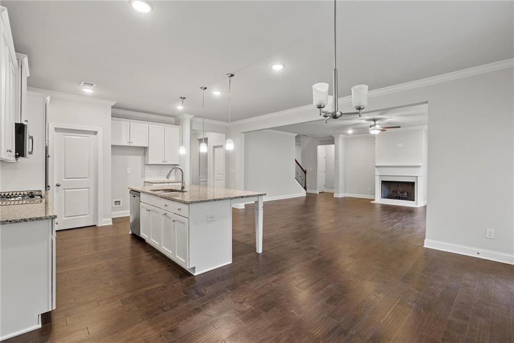 3455 Spring Pl Court Loganville, GA 30052 - Photo 17 of 42 a large kitchen with kitchen island a stove a sink a refrigerator and white cabinets with wooden floor