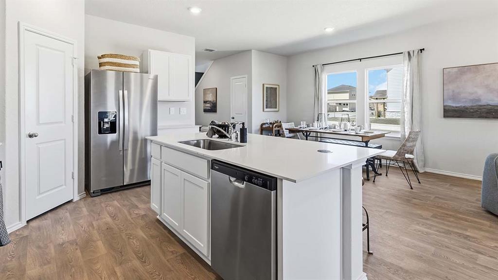 226 Pheasant Run Road Terrell, TX 75160 - Photo 23 of 36 Kitchen featuring a large island with white cabinetry and an undermount sink, stainless steel appliances, and wood-finish flooring