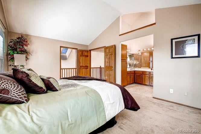 8205 Sweet Water Road Lone Tree, CO 80124 - Photo 16 of 33 a bedroom with a large bed and a chandelier