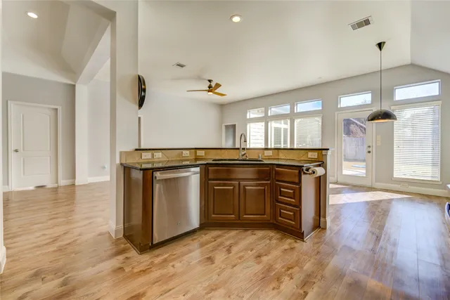 a kitchen with stainless steel appliances granite countertop a sink a stove and a wooden floors