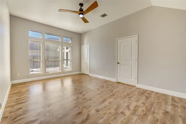 a view of an empty room with a window and wooden floor