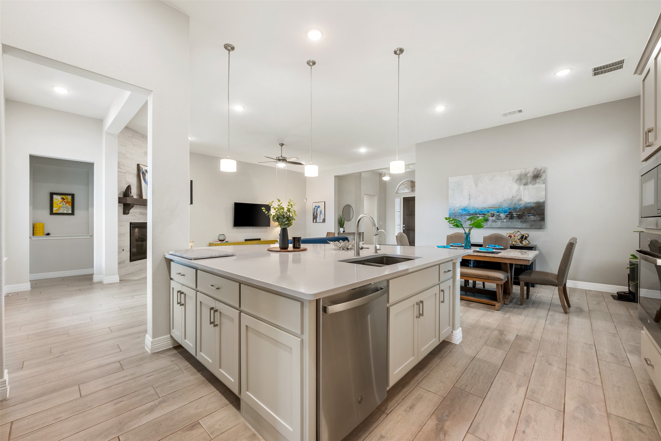 2501 Costera Street Leander, TX 78641 - Photo 40 of 40 Kitchen featuring decorative light fixtures, open floor plan, stainless steel dishwasher, wood finish floors, and a large fireplace