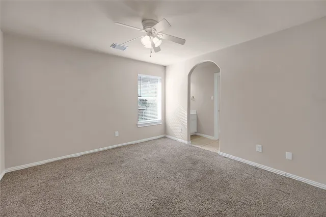 an empty room with windows and chandelier fan