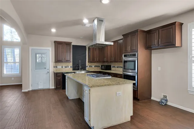 a view of kitchen with stainless steel appliances granite countertop a stove top oven a refrigerator a sink and dishwasher with wooden floor