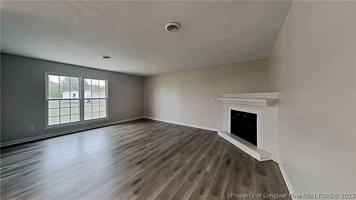 6536 Grist Mill Road Fayetteville, NC 28314 - Photo 5 of 20 a view of empty room with wooden floor and fireplace