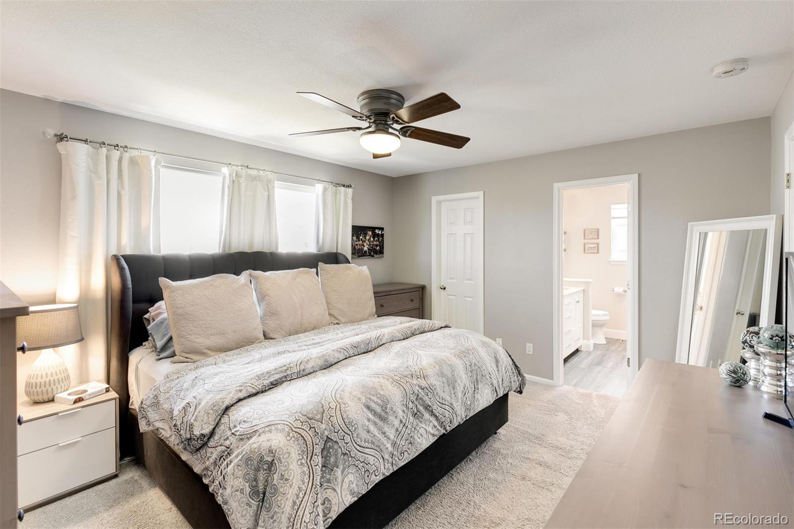 877 Timbervale Trail Highlands Ranch, CO 80129 - Photo 19 of 34 a bedroom with a large bed and a chandelier