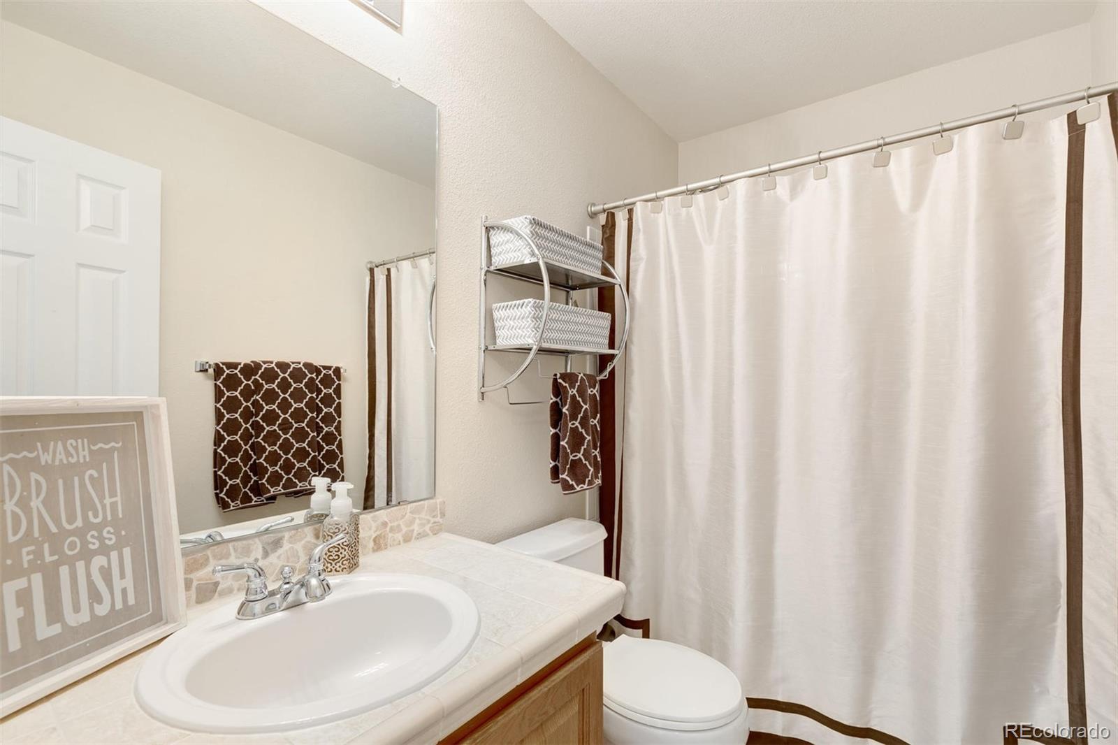 877 Timbervale Trail Highlands Ranch, CO 80129 - Photo 23 of 34 a bathroom with a sink a toilet and shower curtain