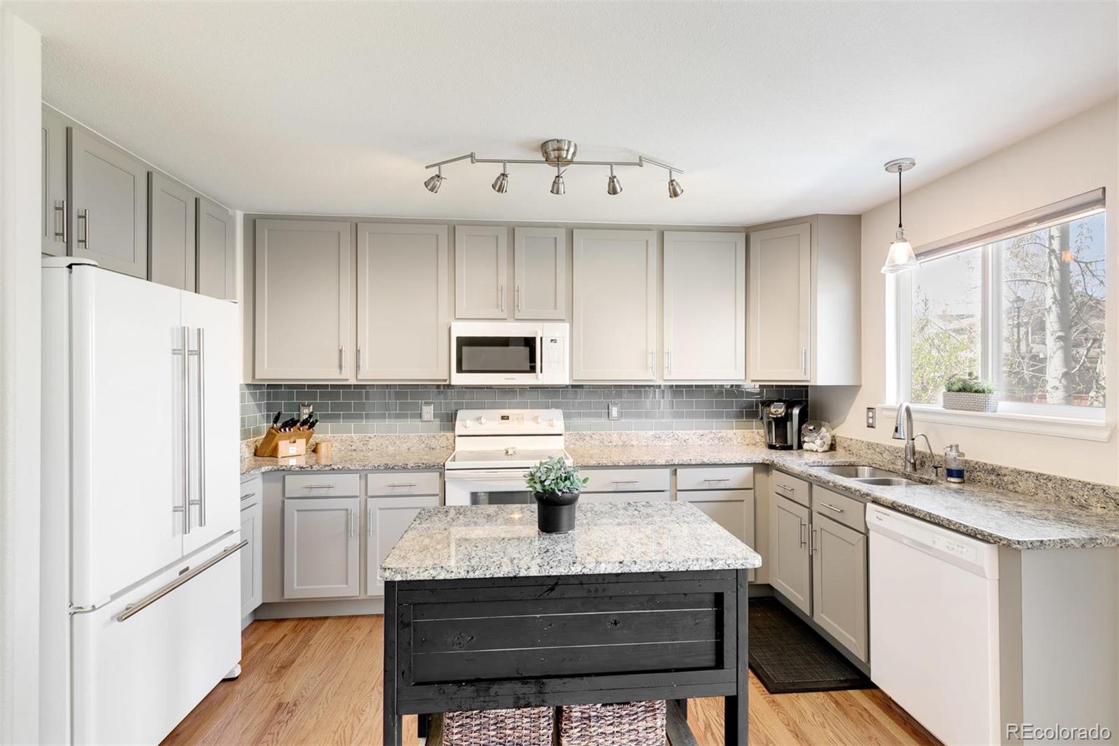 877 Timbervale Trail Highlands Ranch, CO 80129 - Photo 10 of 34 a kitchen with granite countertop a sink stainless steel appliances and white cabinets