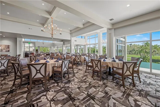 a room with lots of tables a large window and chairs