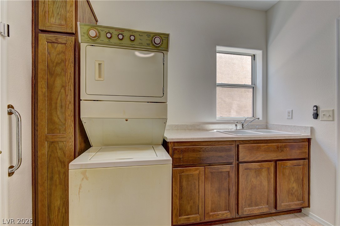 3013 Fort Stanwix Road Henderson, NV 89052 - Photo 15 of 26 Laundry room featuring cabinet space, stacked washer / dryer, and light tile patterned floors