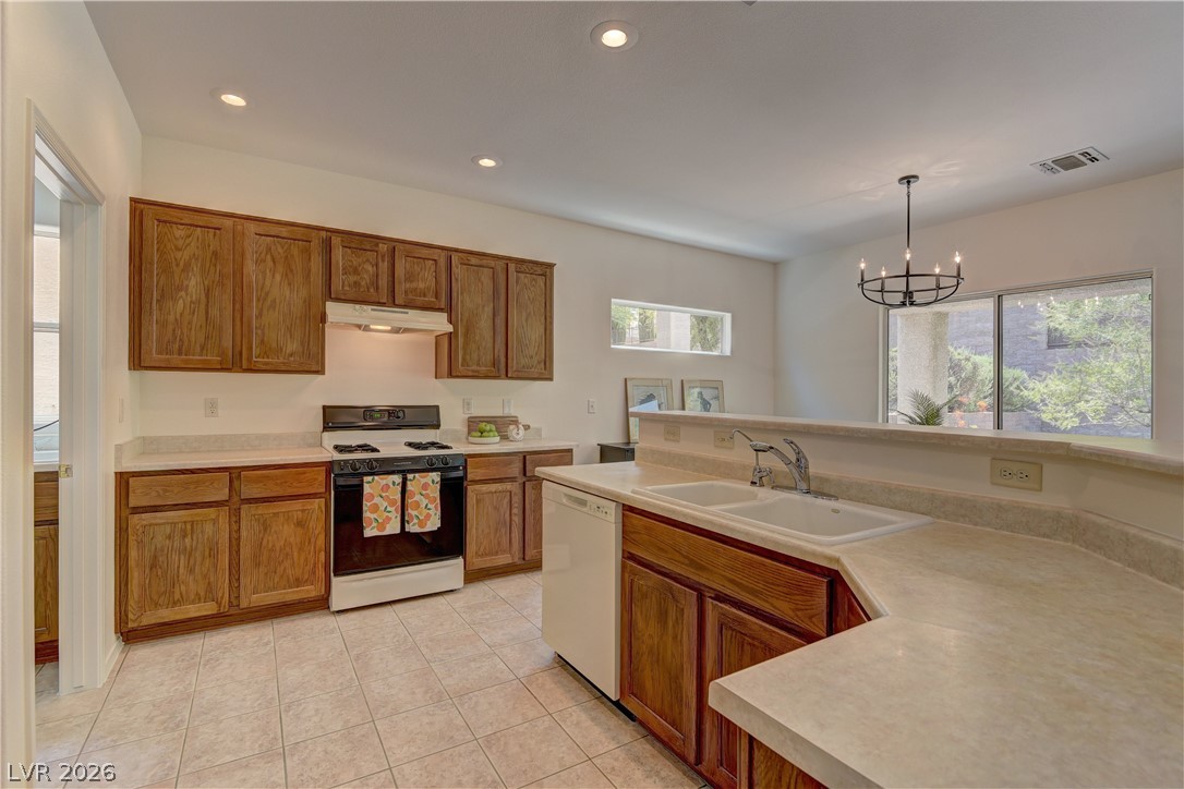 3013 Fort Stanwix Road Henderson, NV 89052 - Photo 8 of 26 Kitchen with gas range oven, wood finish cabinets, light countertops, dishwasher, and a chandelier