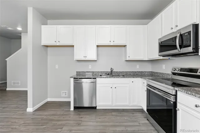 a kitchen with stainless steel appliances granite countertop a stove a sink and a microwave