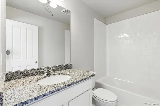 a bathroom with a granite countertop sink a toilet and shower