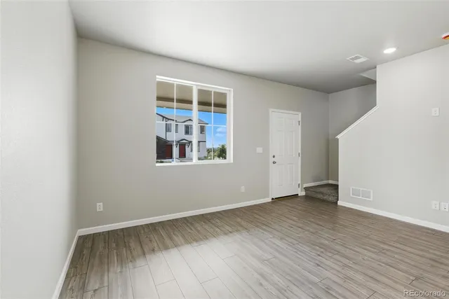 an empty room with wooden floor and windows